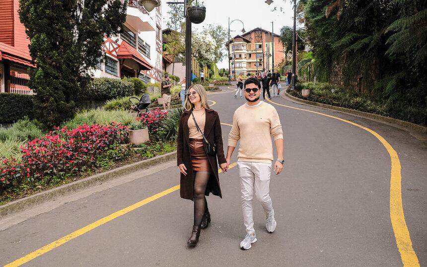 Casal caminhando por uma avenida florida da Serra Gaúcha