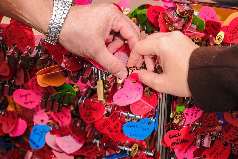 Casal prendendo um cadeado na Fonte do Amor Eterno, em Gramado